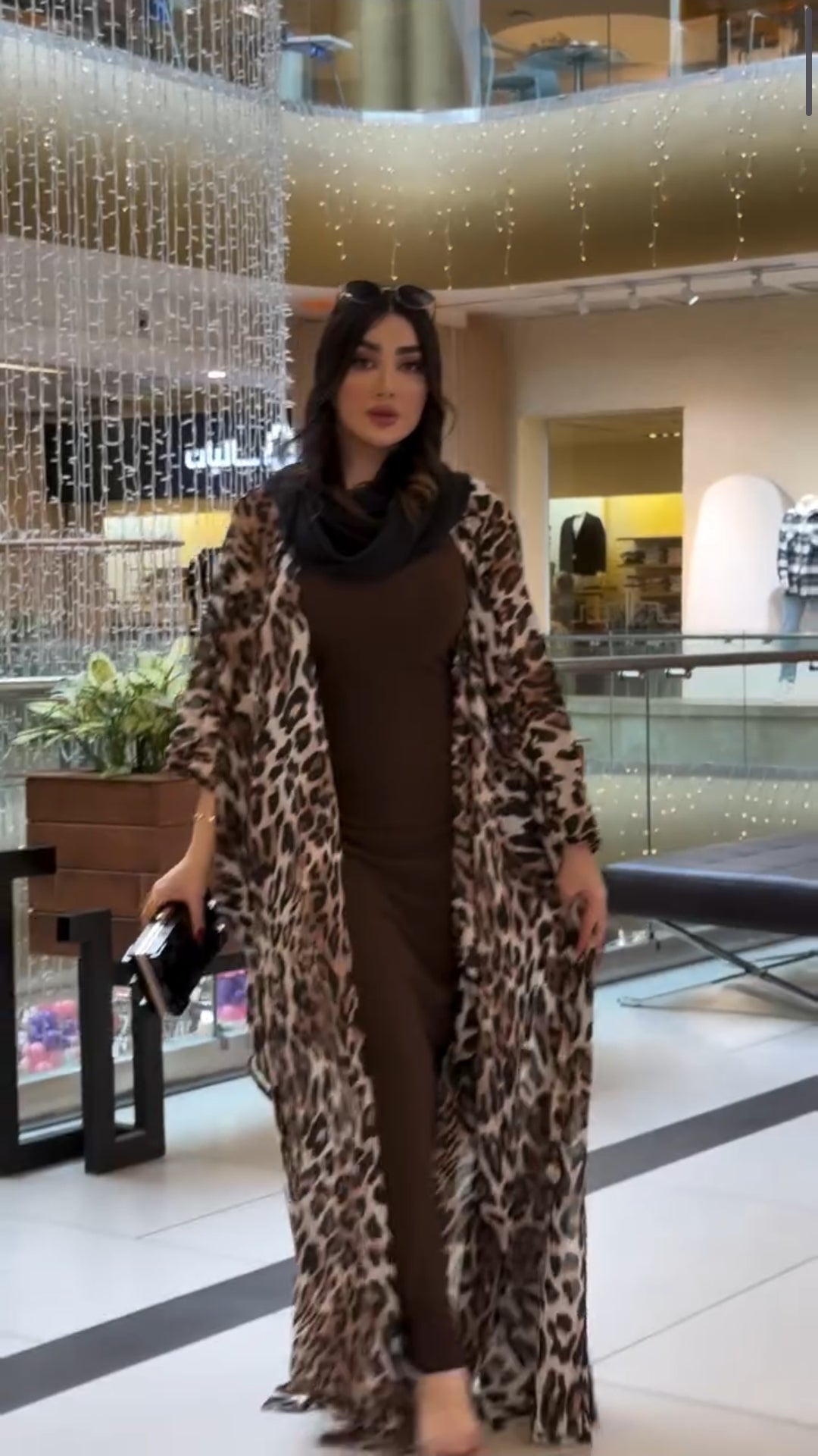 Woman wearing a leopard print coat in a shopping mall setting