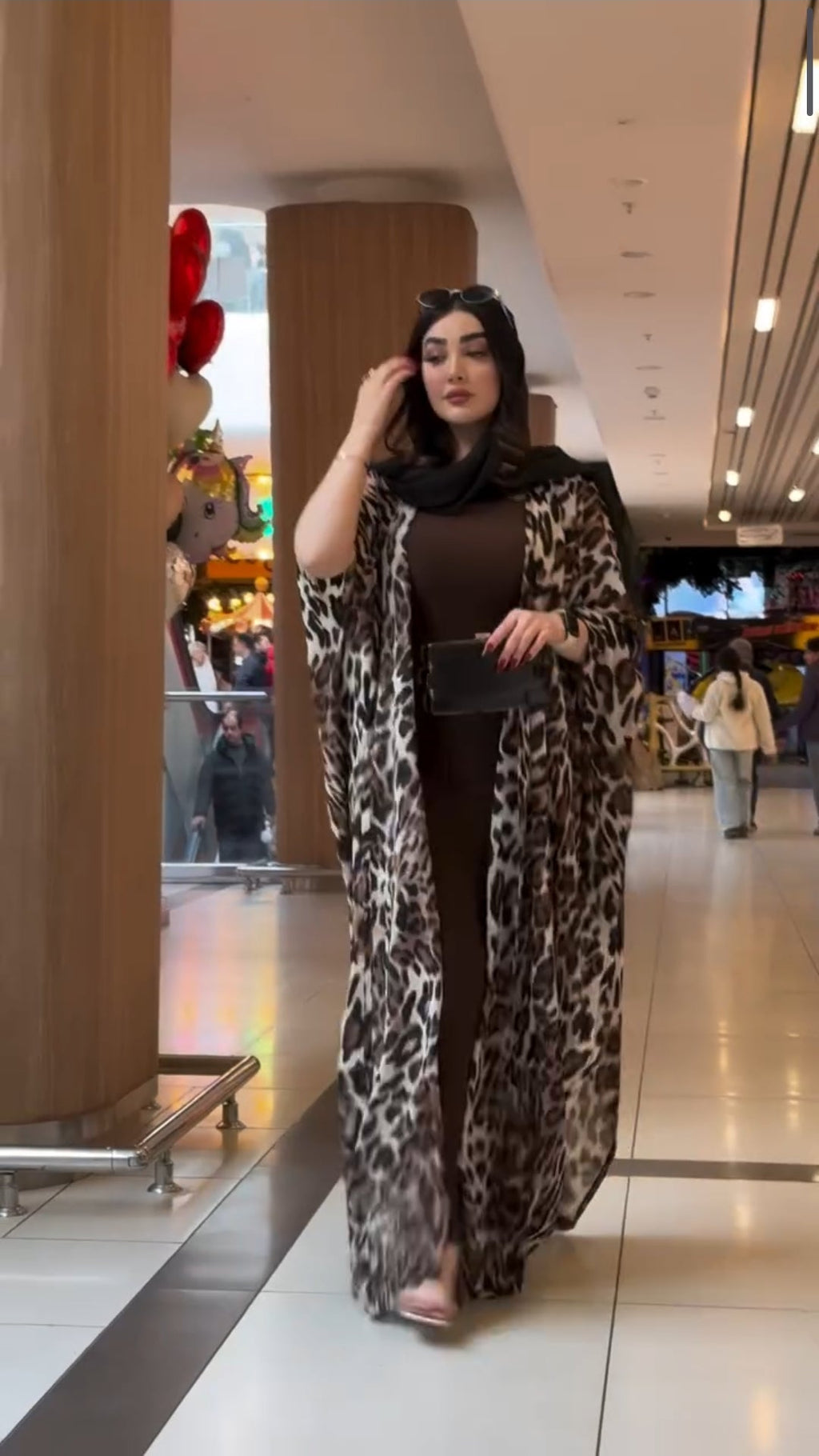 Woman in a leopard print dress and brown top in a mall setting