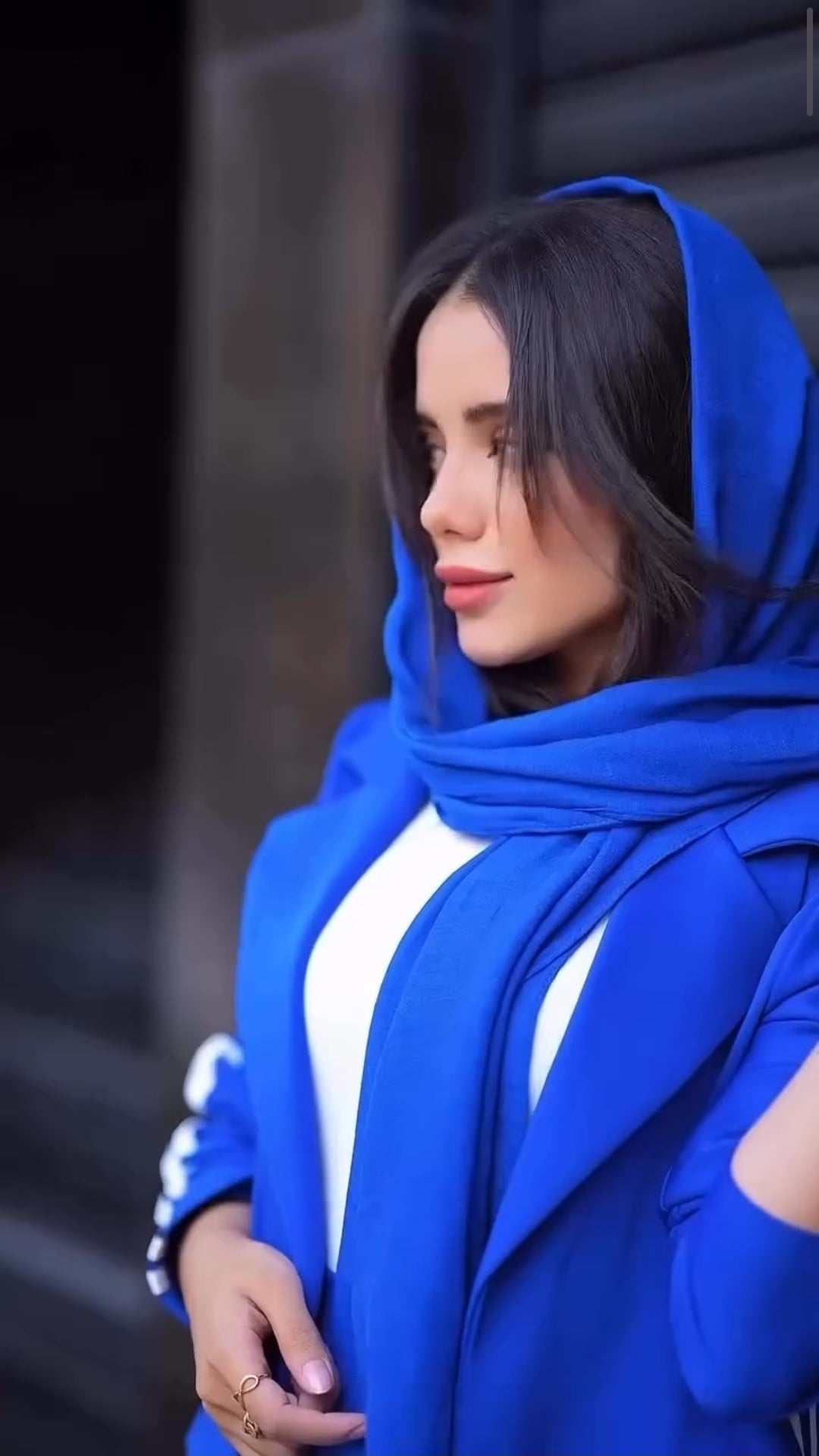 Woman wearing a blue hijab and coat against a blurred background